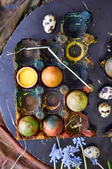 colored dark pallet with eggs for Easter stands on a black board on a table, top view