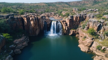 Waterfall Cascading Into Lush Green Pool Surrounded by Rocky Cliffs