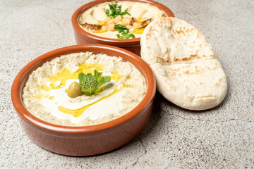 Baba ghanoush and hummus served with pita bread and olive oil on rustic table