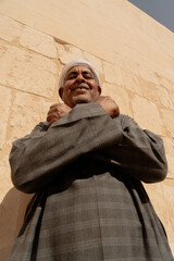Photo of an Arab man wearing a white turban and traditional clothing with traditional patterns, smiling as he poses for the photo. Travel to Egypt. Valley of the Kings