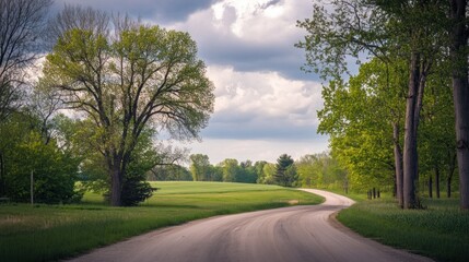 A Winding Dirt Road Through Lush Green Trees And Fields