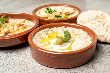 Hummus and baba ghanoush with pita bread and olive oil on gray background