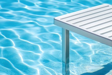 Obraz premium White pool ladder in clear blue water, sunlight reflecting on the surface, creating ripples and waves.
