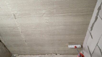 Construction worker applying waterproofing coating on ceiling with paint roller