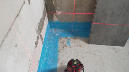 Laser level projecting red beams onto wall and floor during home renovation