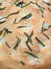 Close up of fresh focaccia bread with salt and rosemary top view just baked