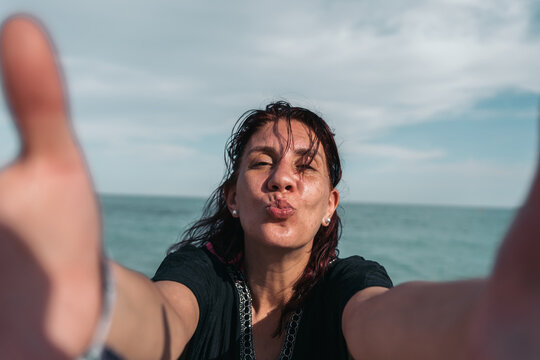 Middle aged woman taking a selfie at the beach on a sunny day - Powered by Adobe