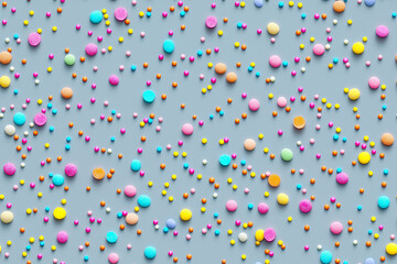 A seamless colorful sprinkles pattern on a soft gray background, with a top-down view of pastel and vibrant candy sprinkles. High-detail 8K resolution, flat lay composition, and space for text