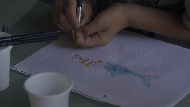 ni&ntilde;o dibujando peces con pincel