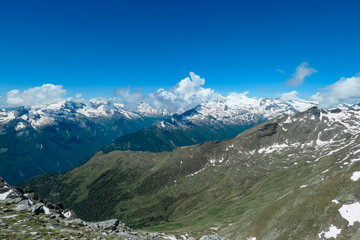 Panoramic vista unfolds form top of mount Reitereck, showcasing snow-dusted mountains under a bright blue sky, revealing the majestic beauty of the Ankogelgruppe and Lieser-Maltatal region in Austria