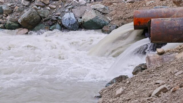 mountain river water flowing through temporary pipe bridge across the mountain river using steel pipes and a soil embankment