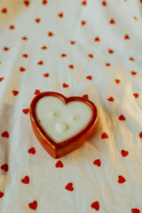 decorative red heart-shaped candle on a white background with red hearts