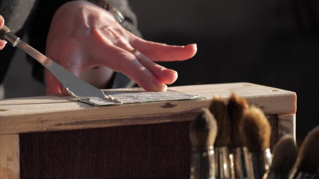 Applying texture paste to a wooden surface using a stencil and spatula