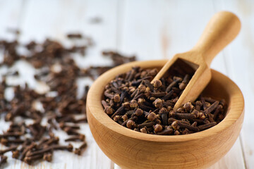 wooden bowl with cloves spice on a white wooden table,  selective focus.