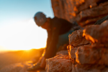 Young girl is preparing for training on the rocks sunset, in the mountains and puts a helmet . Woman engaged in active sports, in mountaineering and rock climbing.