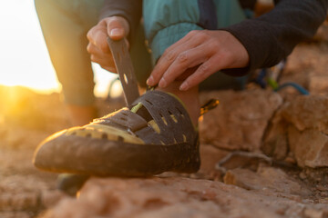 A young girl puts on special climbing shoes on her legs before climbing outdoor training, hands and...