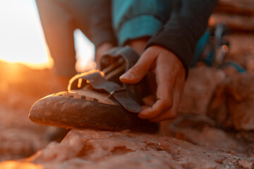 A young girl puts on special climbing shoes on her legs before climbing outdoor training, hands and feet close-up. A woman leads an active lifestyle, is involved in mountaineering and rock climbing.