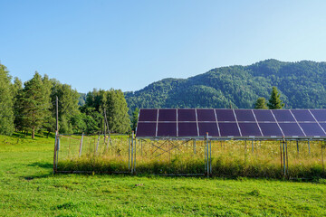 Solar panels in a village surrounded by lush forest and mountain views