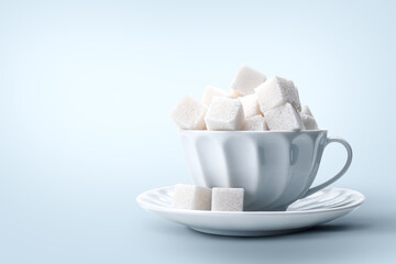 White Sugar Cubes Piled in Teacup for concepts of sweetness, diabetes, sugar consumption, tea time, or health articles about sugar intake.