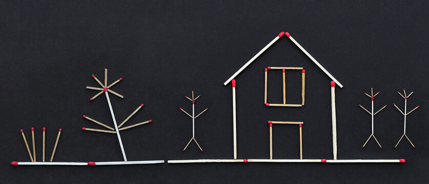 Ein Haus, Menschen und Garten aus Streichh&ouml;lzeren auf schwarzem Papierhintergrund. Zukunftstraum f&uuml;r mietfreies Wohnen