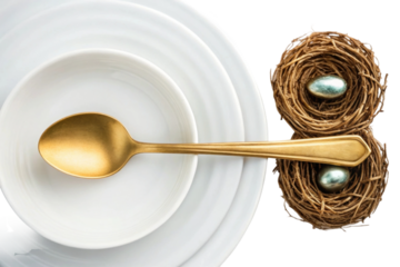 Creative table setting with golden spoon, white plates, and decorative nests with eggs
