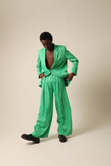 Portrait of African American young man wears green suit and posing over white background. Vertical mock-up.