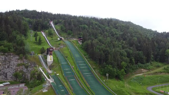 Ski jumps at villacher alpen arena. Drone aerial view of ski jumps at villach in spring, green grass and no snow. overview with camera zooming in or panning