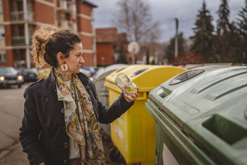 one woman stand with glass garbage in front of recycle containers