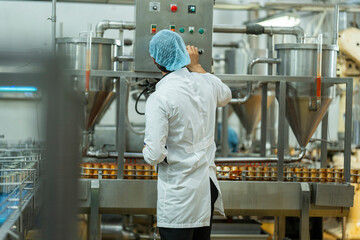 Inspector monitoring canned food production line in an industrial facility Focus on quality control automation and workflow efficiency in food manufacturing.