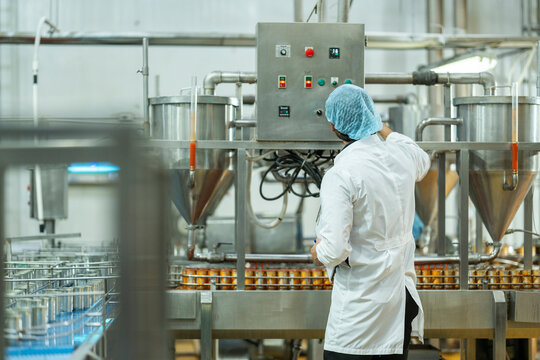 Worker inspecting automated equipment and canned products in a clean production facility Highlights of safety quality assurance and industrial efficiency.