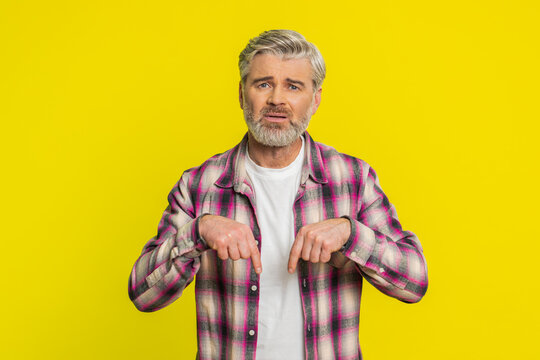 Mature man asking for donations with sincere request expression. Guy gestures with hands pointing down, calling for support for an initiative or project help donations, emotions of gratitude and hope