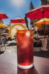 Un vaso alto con campari, vermú rojo y soda, decorado con una rodaja de limón