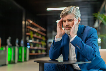 Tired ill middle-aged businessman suffering from headache problem tension and migraine, stress in...