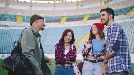 A group of multiracial students say hello and have fun at the stadium during the daytime, enjoying unforgettable meetings and lively communication