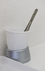 In the dentist's office there is a  Cup with Spoon on Gray Base