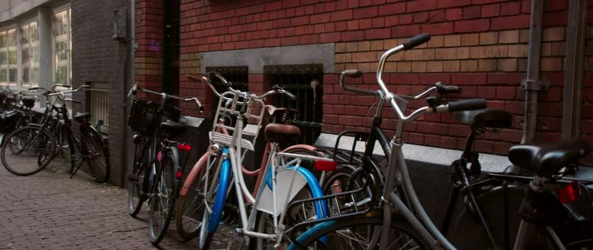 A row of bicycles neatly lined up against a weathered brick wall in an urban environment
