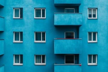 Fototapeta premium Bright blue apartment building with balconies and windows