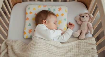 Peaceful sleep of caucasian baby in crib with teddy bear and star pillow