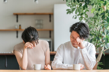 ダイニングテーブルで落ち込むカップル・夫婦（後悔・詐欺・騙される）

