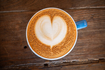 A hot Cappuccino coffee serving on wooden table.