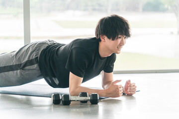Fototapeta premium スポーツジムでプランク・腕立て伏せ・ワークアウト・筋トレ・ボディメイクをするアジア人男性 