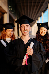 Obraz premium Group of cheerful multiracial graduates holding diplomas, celebrating graduation day
