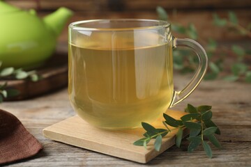Glass cup of aromatic eucalyptus tea on wooden table, closeup