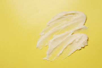 Sample of body scrub on yellow background, top view. Space for text