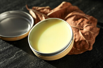 Natural solid perfume and dry leaf on black table, closeup