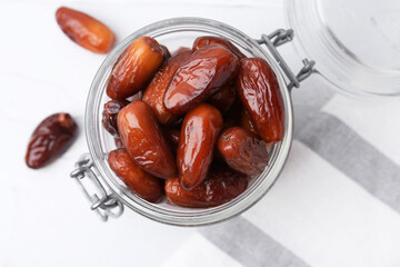Tasty dried dates in jar on white table, top view