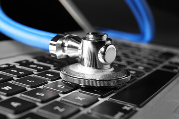 Technical support concept. Stethoscope on laptop keyboard, closeup