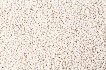 Pile of plastic granules as background, top view