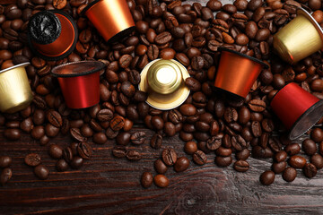 Coffee capsules and beans on wooden table, flat lay