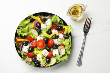 Delicious fresh Greek salad served on white marble table, flat lay